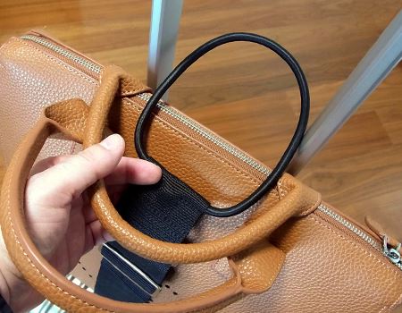 ベルトの上にバッグをのせ、もう片方の輪っかをスーツケースの取っ手に引っかけて固定すれば終了。ベルトの長さはカバンにあわせて調整します