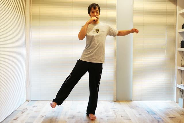 2.片足を浮かせて外側に開く。それと同時に、対角側の腕を上げる